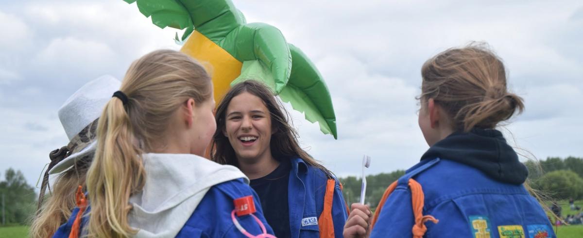 Drie KSA'ers die aan het spelen zijn voor een opgeblazen palmboom.